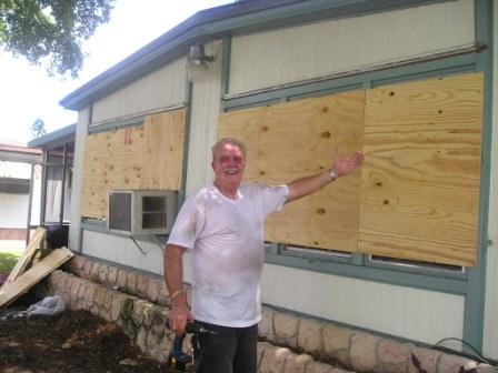 Un batran in Florida acoperind ferestrele cu niste placi  de lemn de protectie inaintea furtunii.